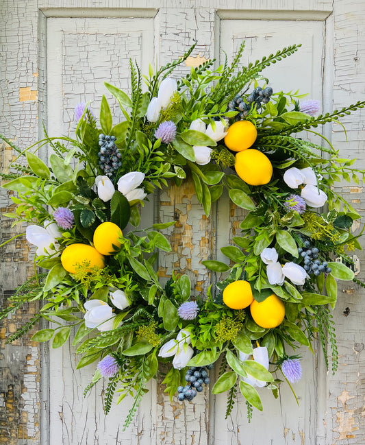 Meyer Grove citrus greenery wreath with lemons, tulips, and mixed greenery styled on a vintage farmhouse door. Botanical spring front door wreath