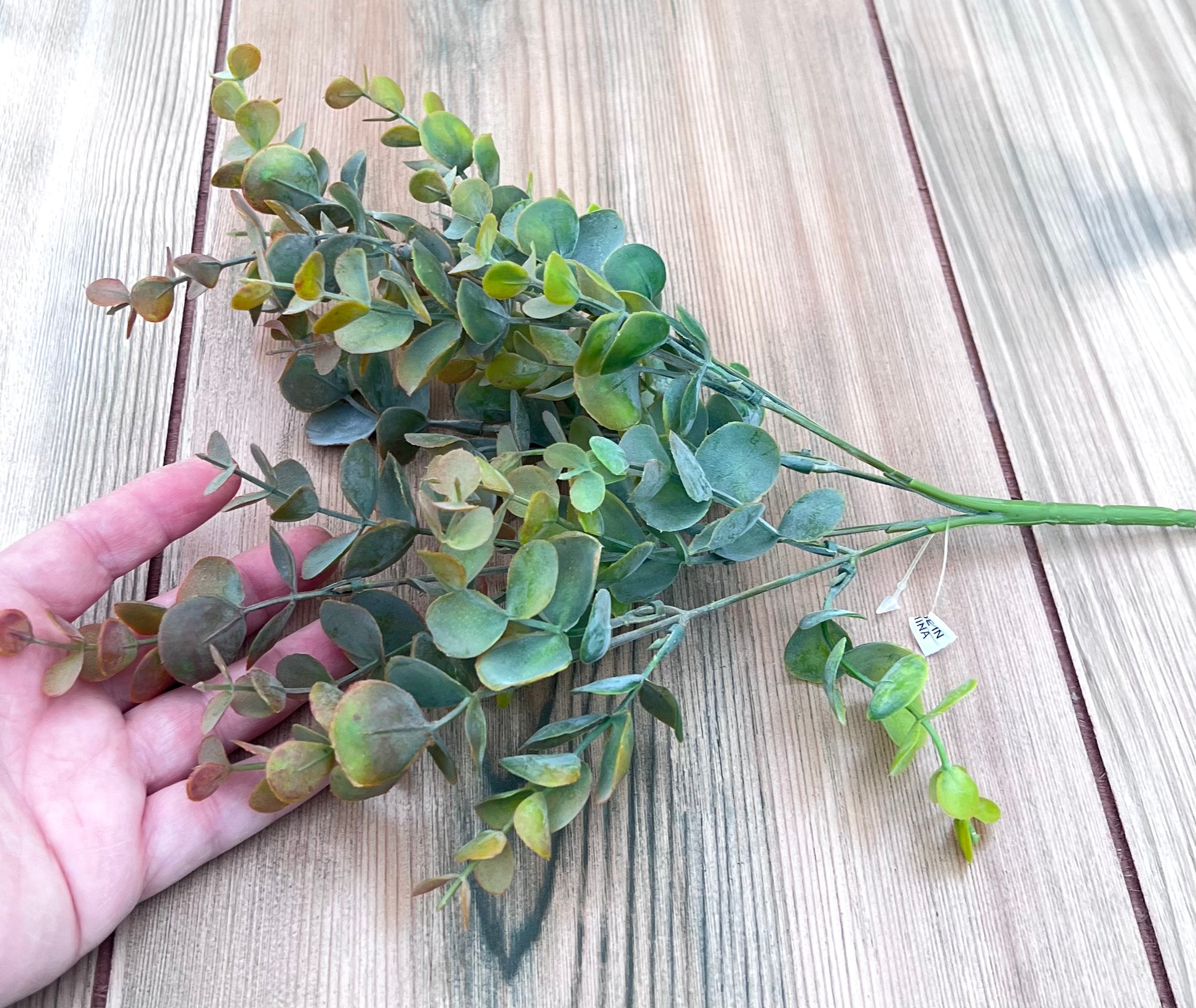 Bronze Tips artificial eucalyptus bush shown in hand for size and scale reference