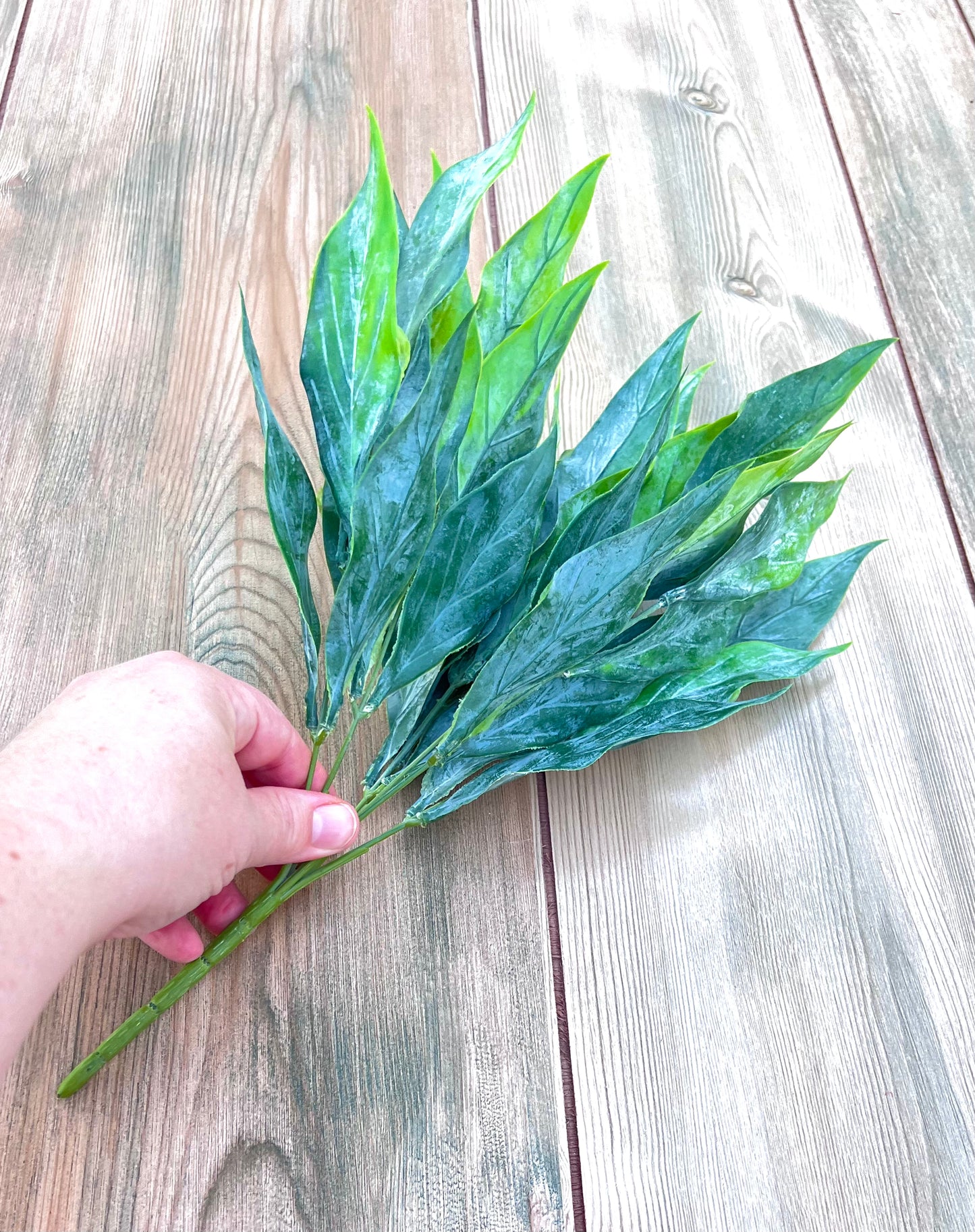 Faux Leaf Bush- Green Tips viewed with a hand to display the overall size, scale, and stem length