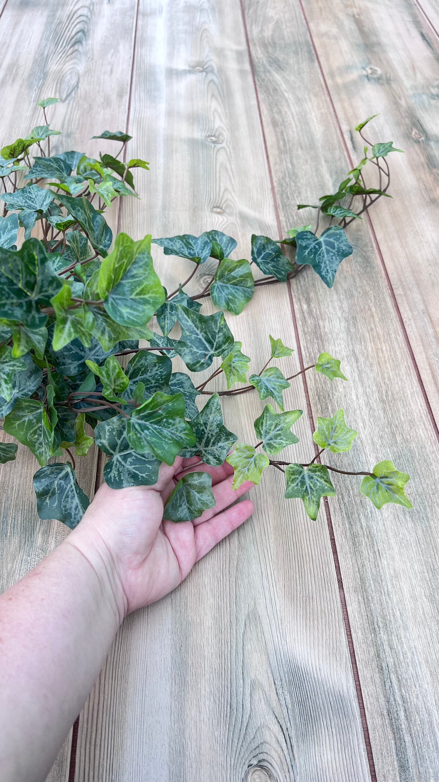 Scale reference of Hanging Ivy Bush — Frost faux greenery bush shown in hand for size comparison