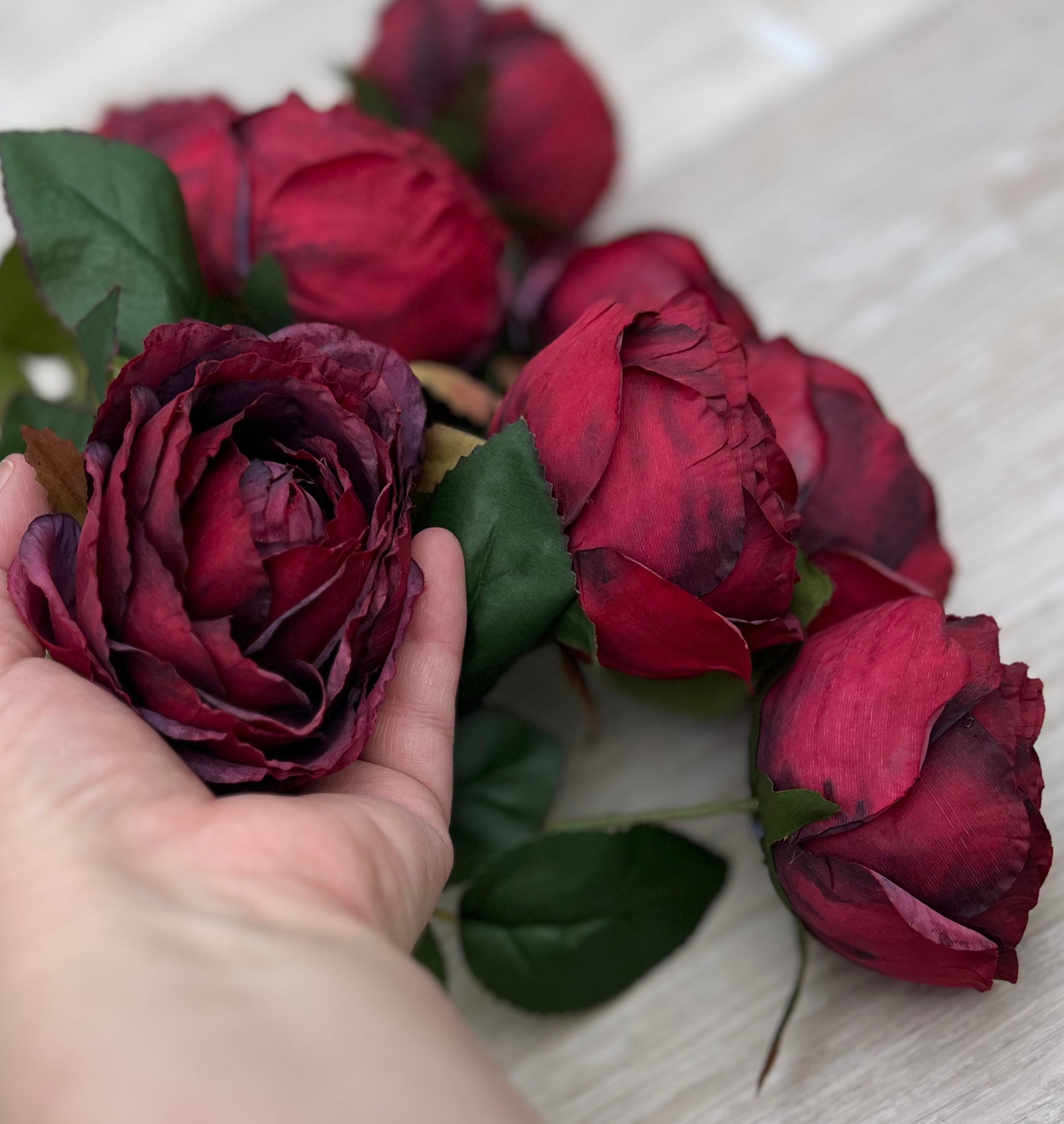 Artificial Cabernet Cabbage Rose bush shown in hand for size and scale reference