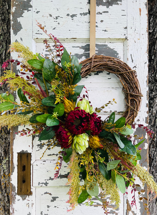 Handcrafted Autumn's Garden Botanical wreath with burgundy sunflowers, artichokes, and greenery for fall front door decor by Gardenbug Designs.