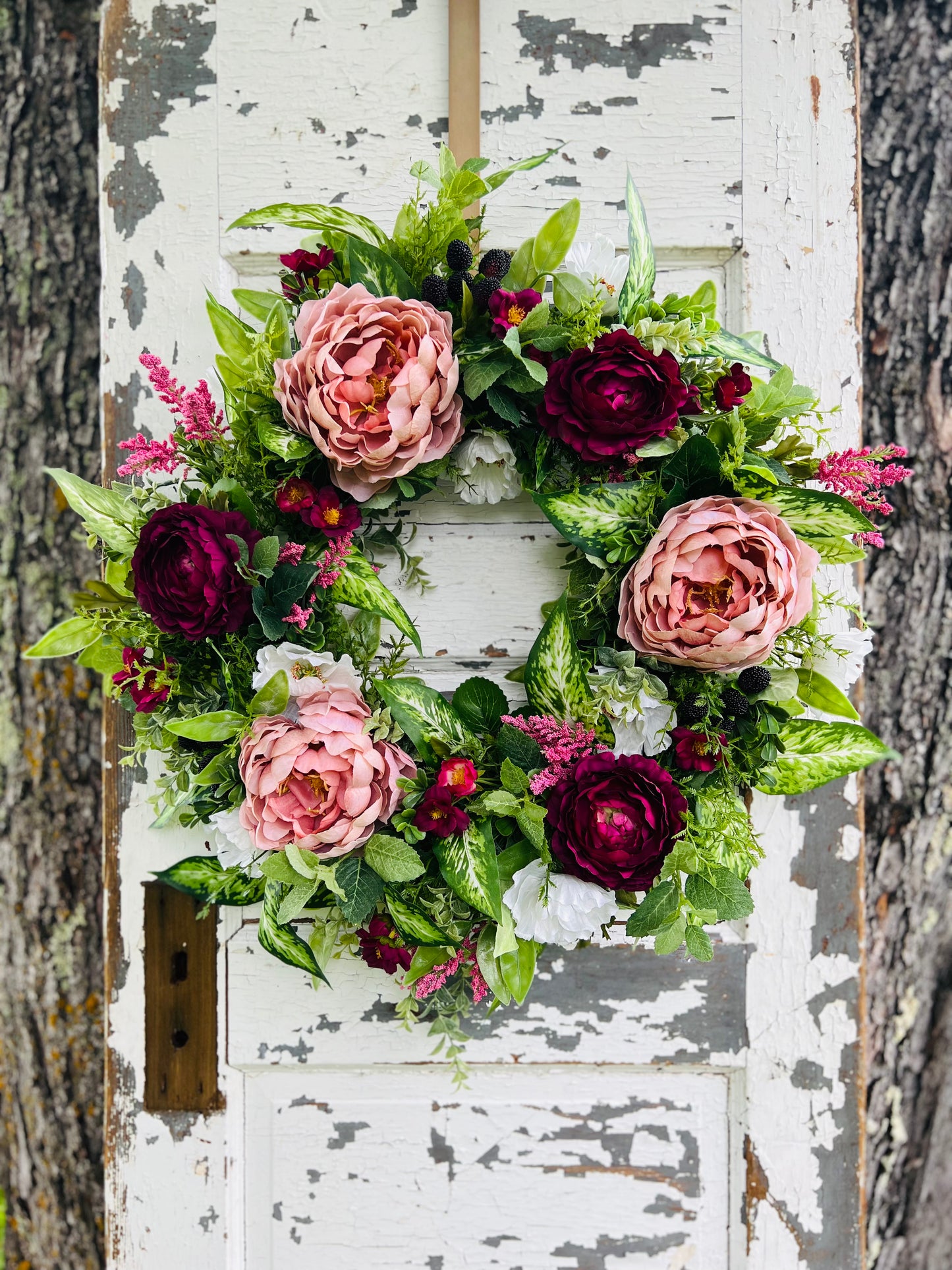 Blackberry Bourbon floral front door wreath featuring peonies, ranunculus, lush greenery, and blackberry accents styled on a rustic entry door | Gardenbug Designs.