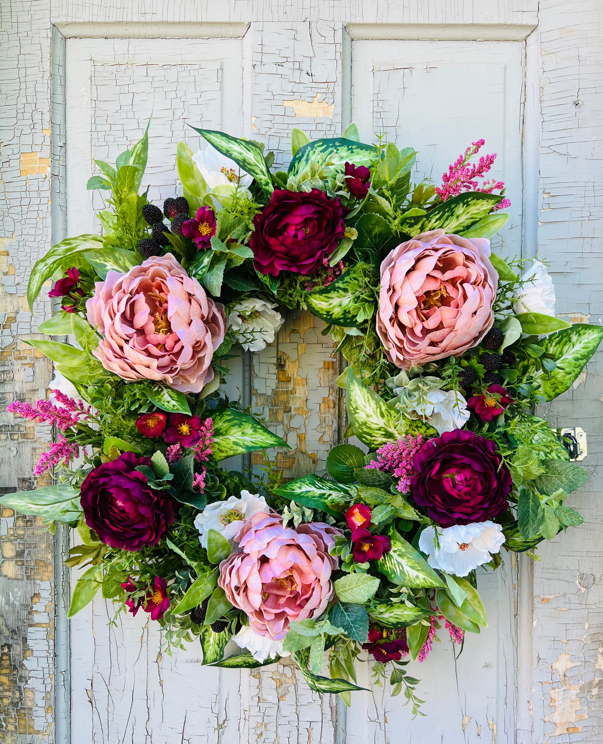 Blackberry Bourbon floral wreath design featuring layered florals, faux blackberries, and realistic greenery arranged in a balanced garden composition and showcased on a vintage door | Gardenbug Designs