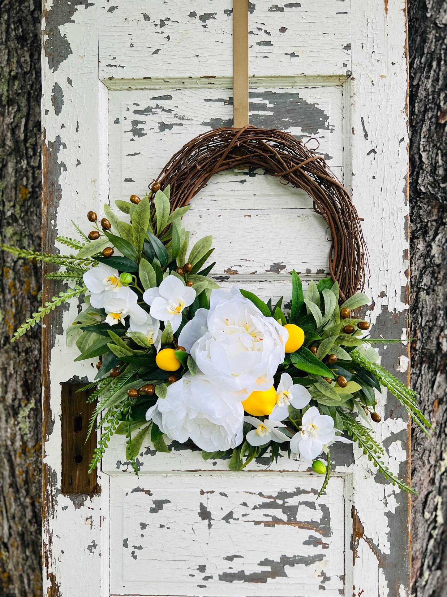 Martini citrus and white floral wreath highlighting an asymmetrical arrangement styled on a rustic wooden door