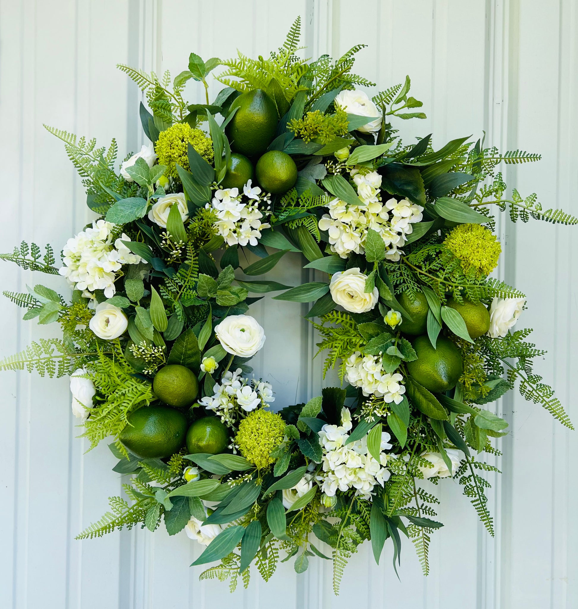 Mojito summer botanical wreath design featuring layered greenery and citrus accents displayed on white metal siding | Gardenbug Designs
