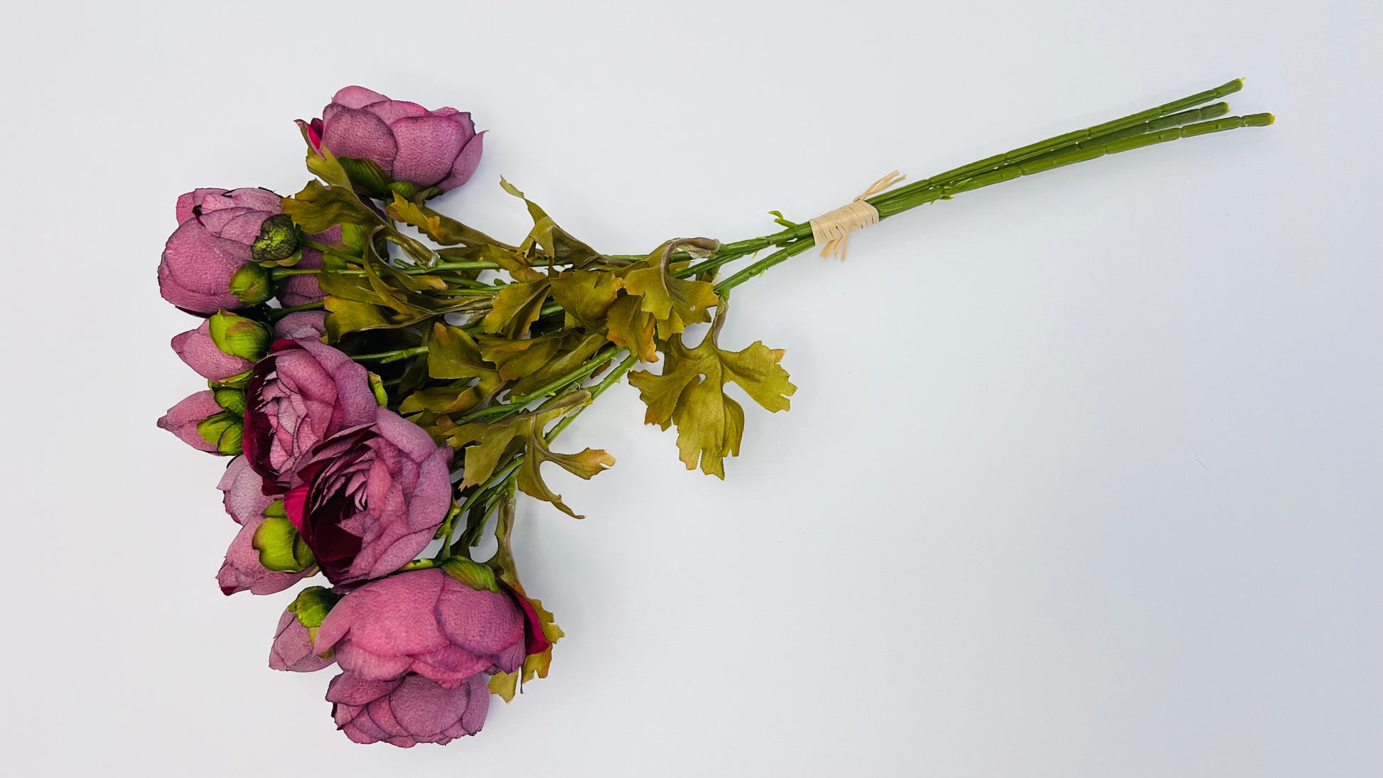 Burgundy ranunculus bundle arranged horizontally with extended stem length and directional bloom placement suited for flexible floral styling