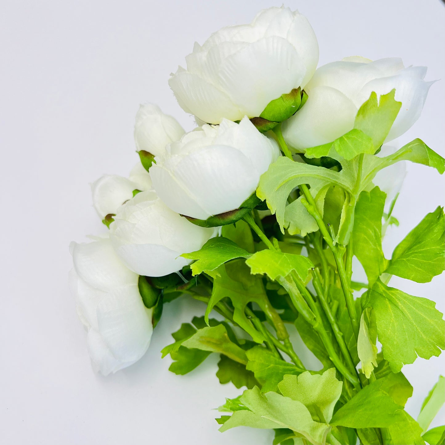 Back view of white ranunculus bundle showing layered stems, leaf placement, and realistic greenery construction