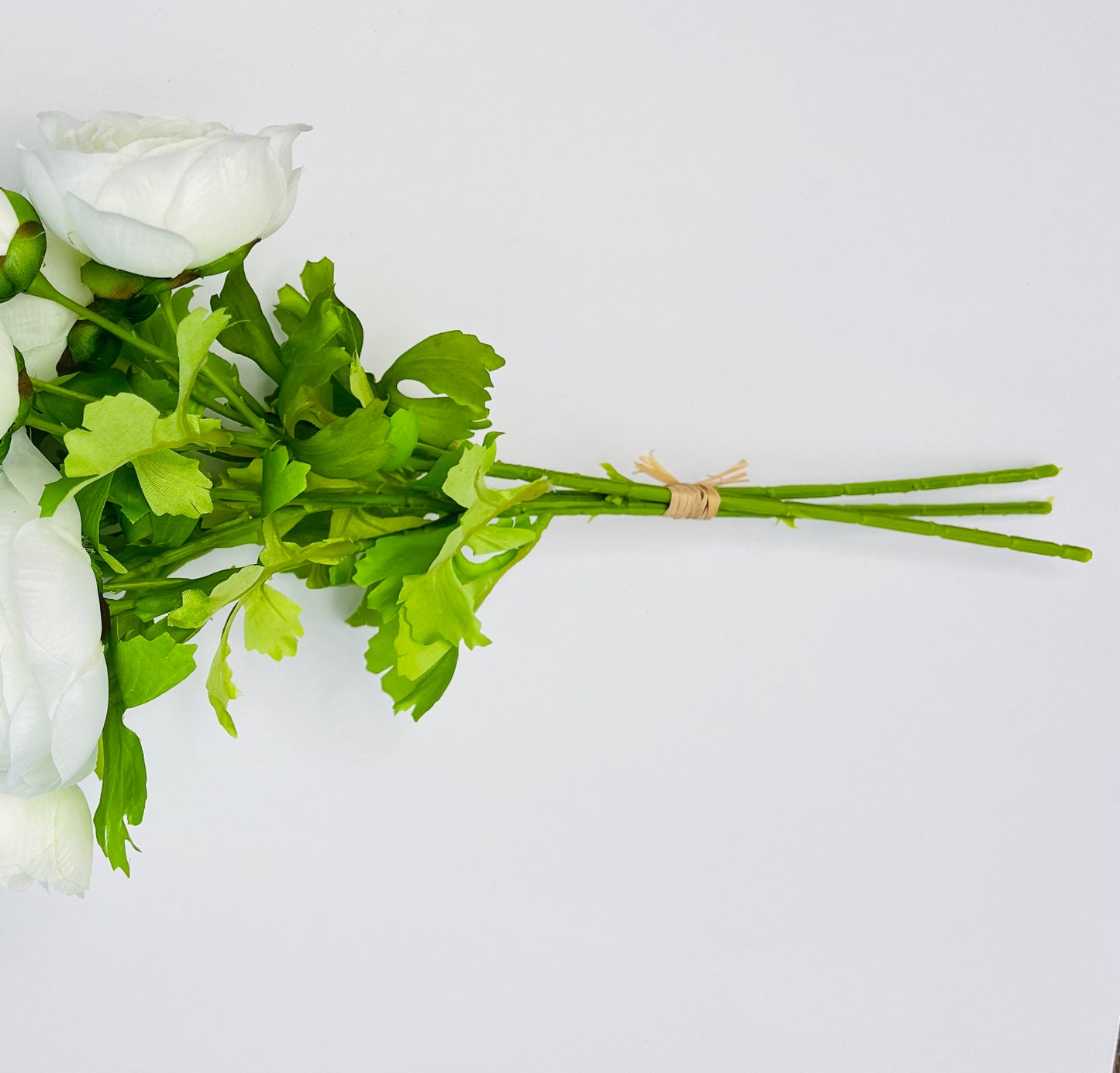 White ranunculus bundle shown from the side, highlighting the stem length, binding, and construction
