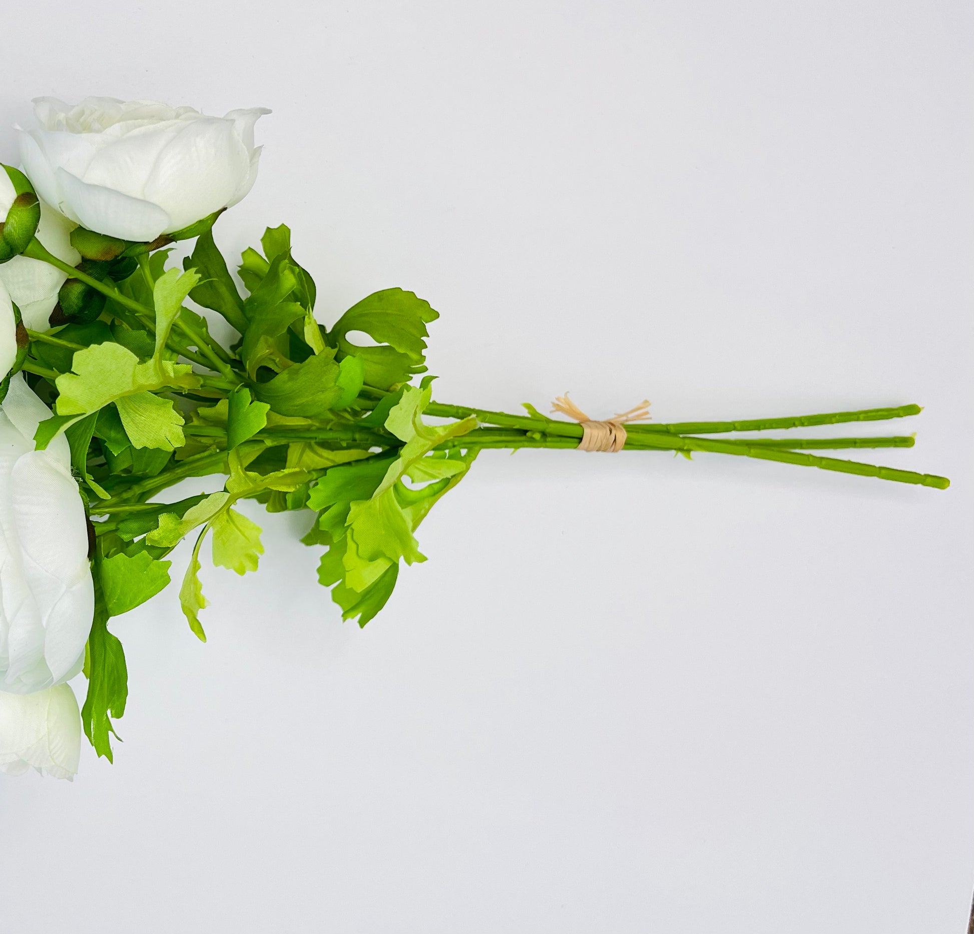 White ranunculus bundle shown from the side, highlighting the stem length, binding, and construction