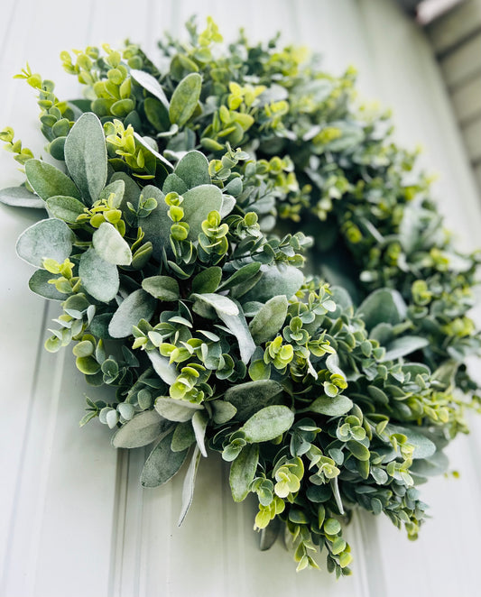 Morning Dawn eucalyptus greenery wreath photographed at an angle on  neutral siding highlighting natural movement and layered botanical foliage